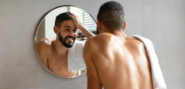 Man managing haircare routine at bathroom mirror